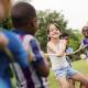 Happy school children playing tug of war with rope in park