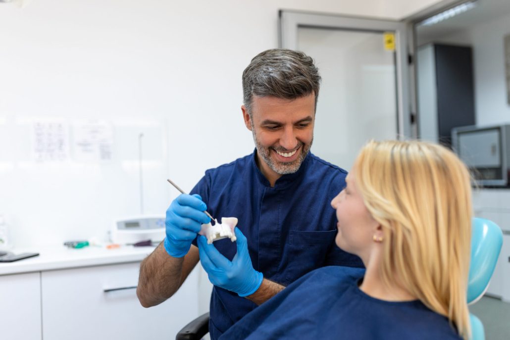 Dentist showing dental plaster mold to the patient. Dentist doctor showing jaw model at dental clinic, dental care concept. Dental care concept.