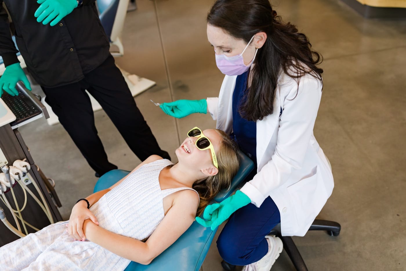 Smiling young patient in yellow sunglasses in the treatment chair with a Blue Ridge Orthodontics team member